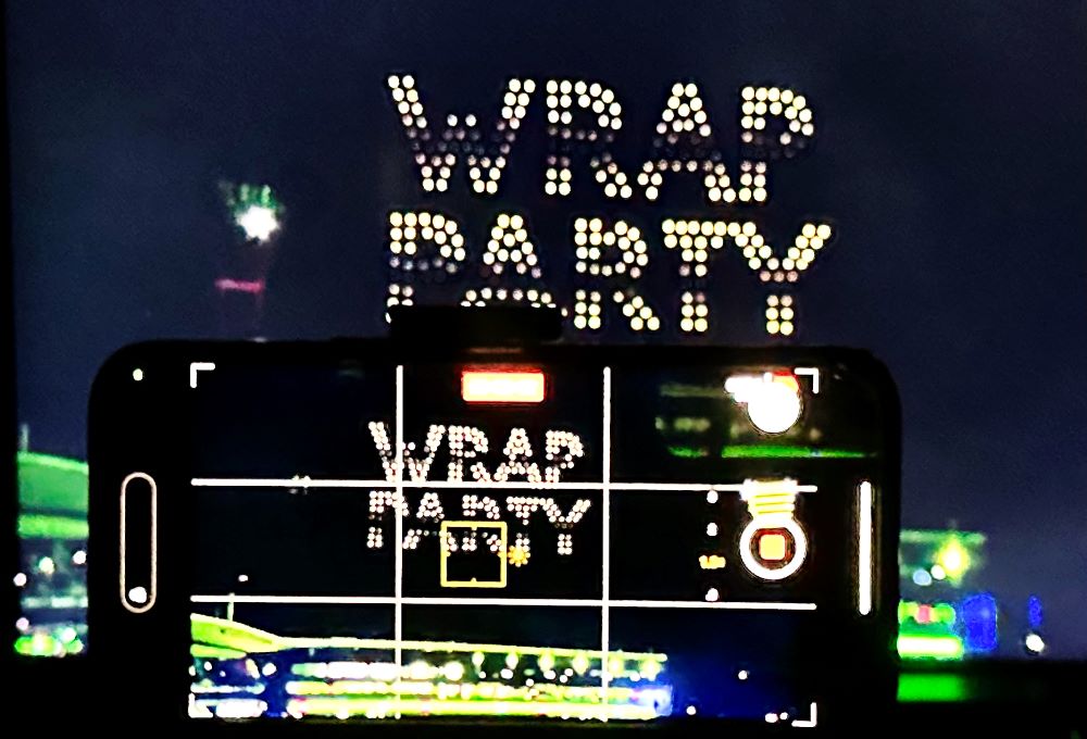 Drone light display spelling 'Wrap Party' at Sydney Thunder Big Bash League event, captured through a smartphone screen with vibrant night lighting.